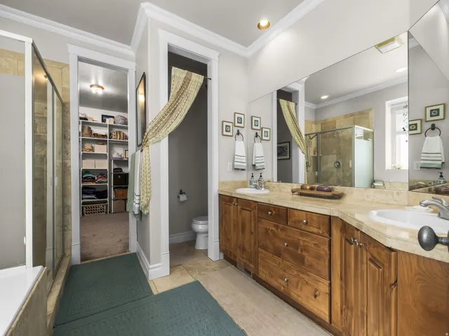 Dual vanity with integrated sinks, wood cabinetry, and a large wall-mounted mirror