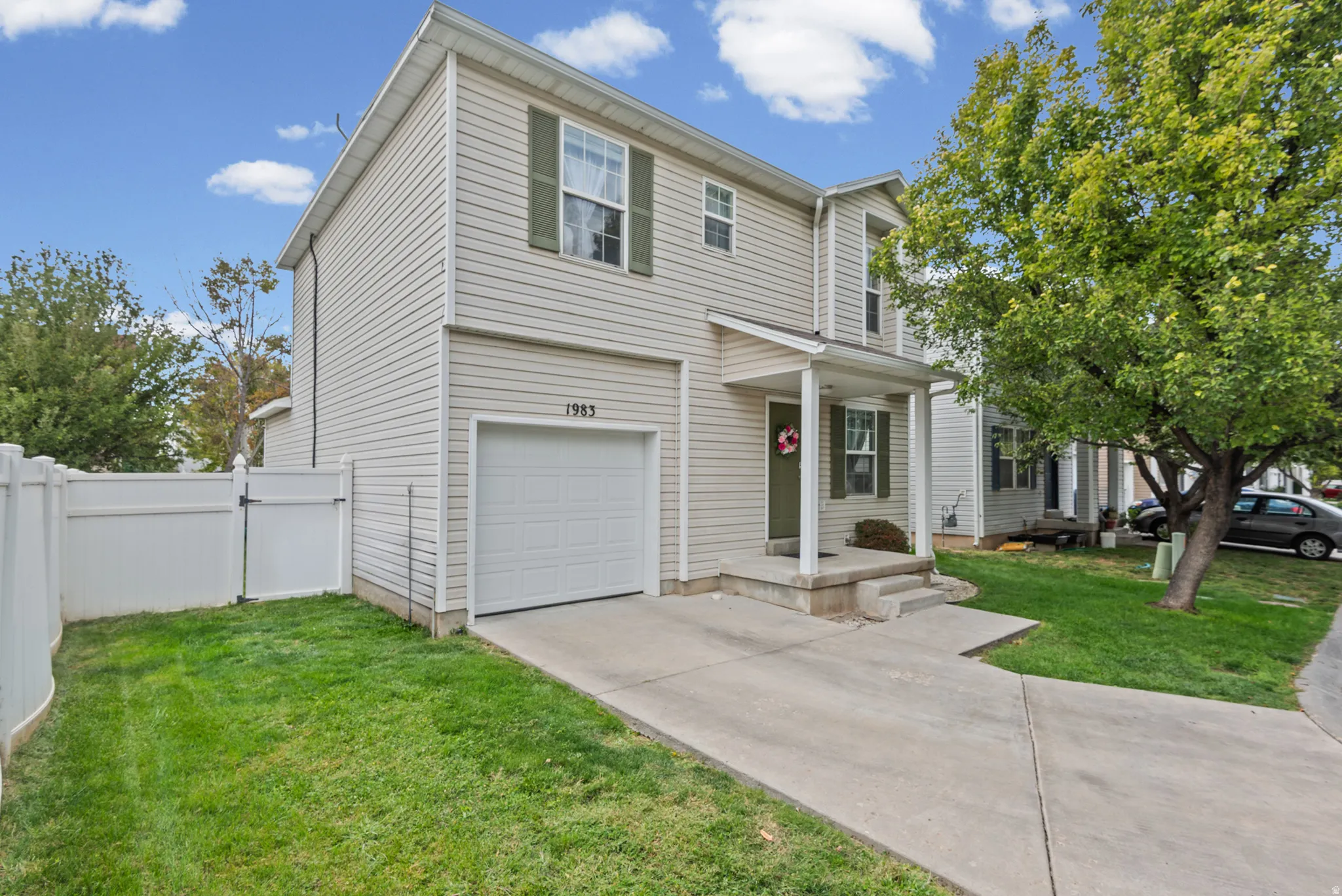 Two-story property with light-colored siding, a covered entry, and a single-car garage