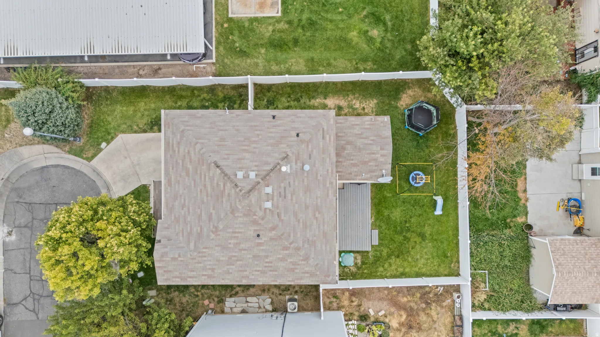 Expansive backyard featuring a manicured lawn, established trees, and a deck