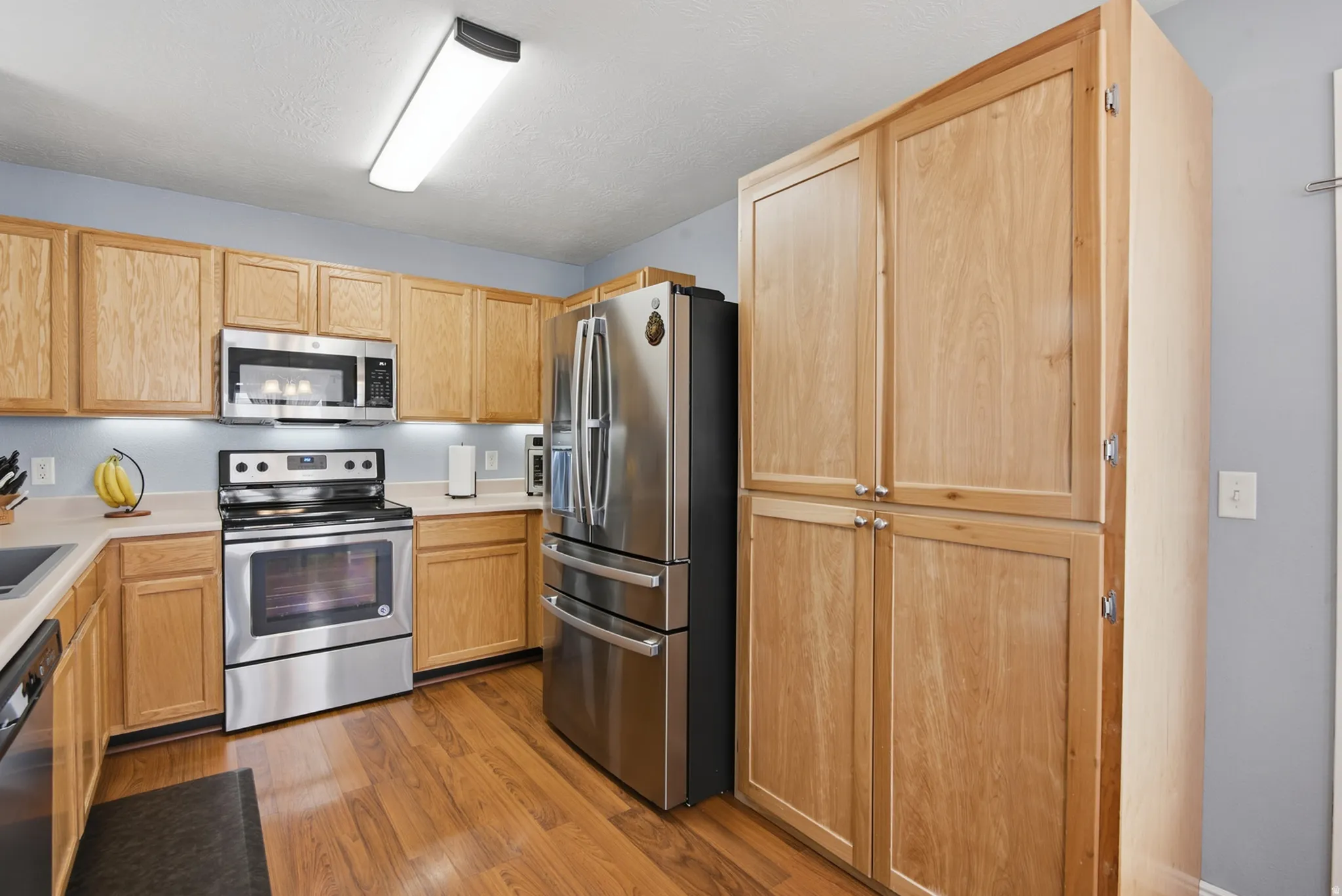 Stainless steel appliances, wood-finish flooring, wood cabinetry, built-in microwave, and ample storage