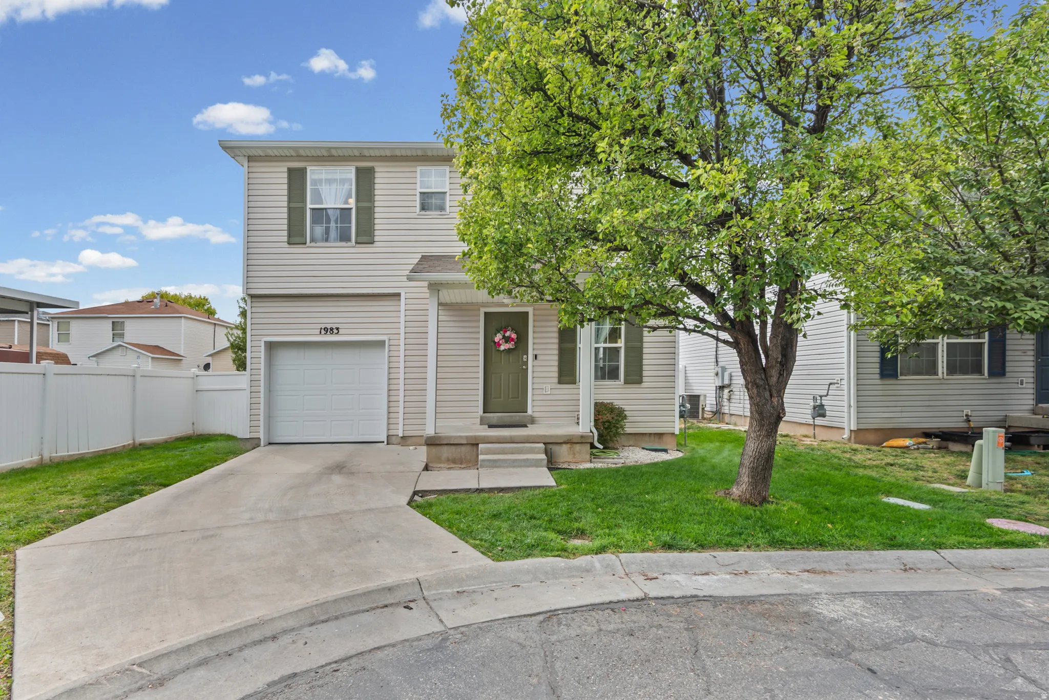 Two-story residence featuring light-colored siding, an attached single-car garage, and a concrete driveway