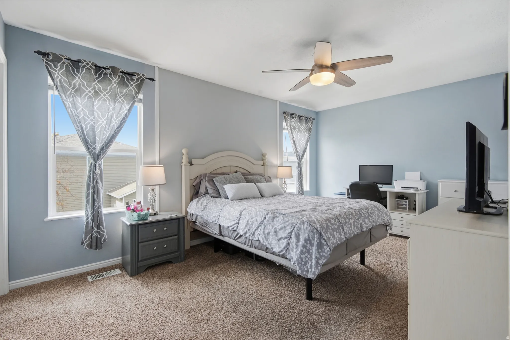 Carpeted flooring, two windows, and a ceiling fan with integrated lighting
