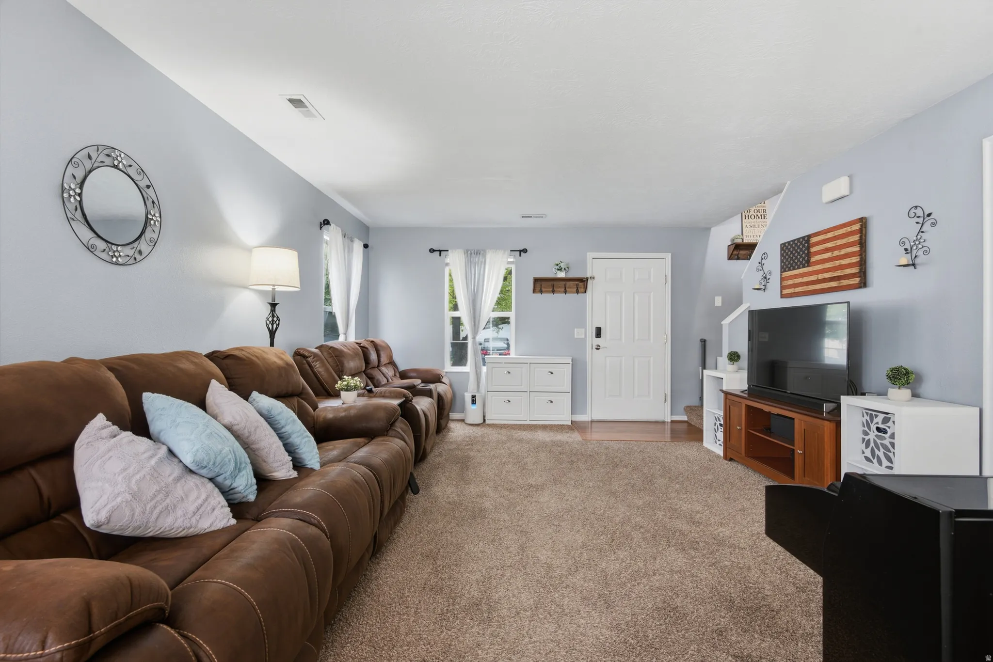 Spacious living area featuring light blue wall paint, a white entry door, and recessed lighting