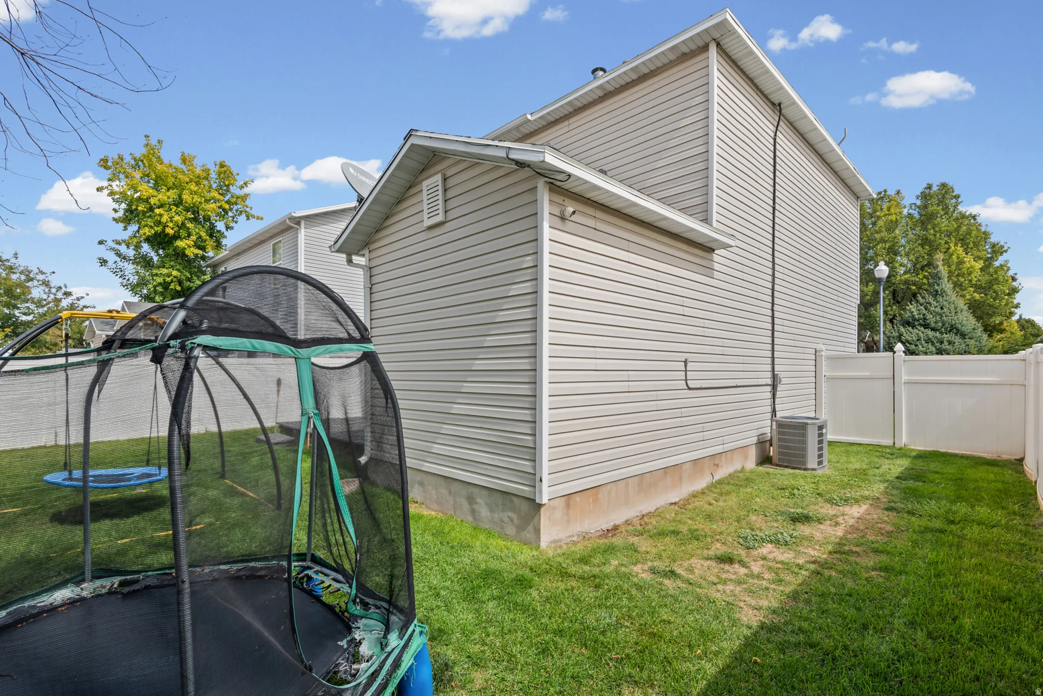 Exterior with vinyl siding, white fencing, and an exposed foundation