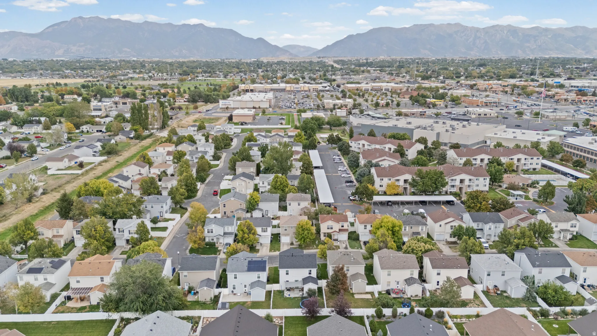Residential neighborhood with varied architectural styles, mature trees, and mountain scenery