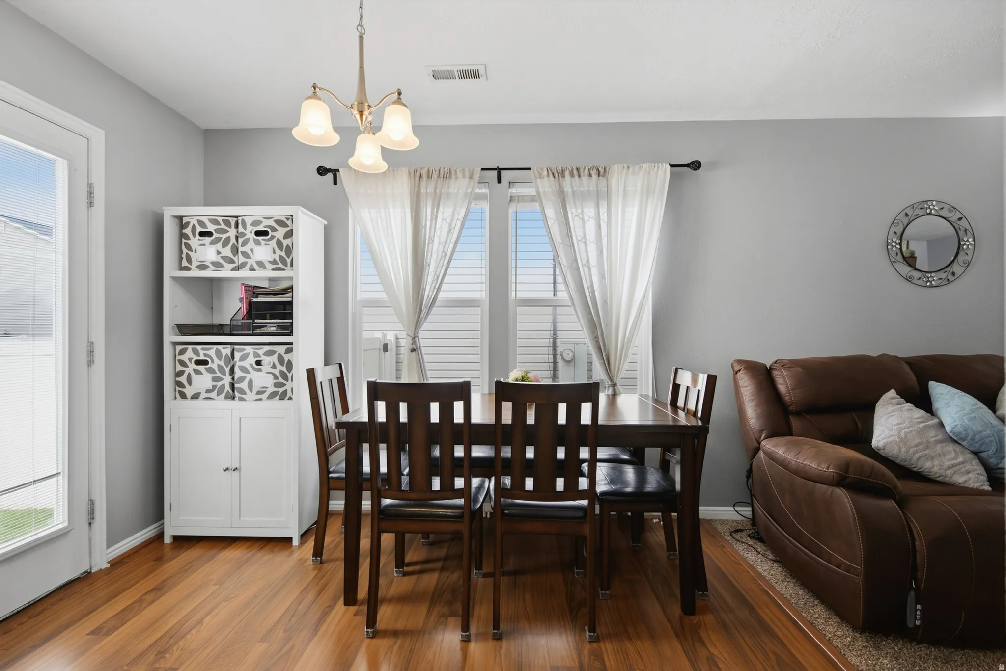 Hardwood flooring throughout, with a white built-in storage cabinet and a chandelier light fixture