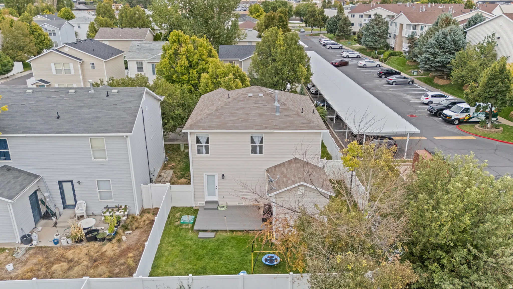Two-story residential structure with a shingled roof, private fenced yard, and a ground-level patio