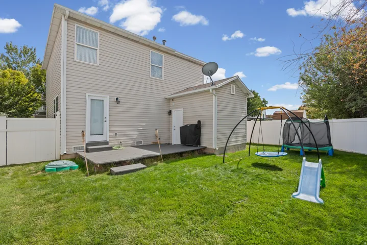 Expansive lawn area with a multi-level patio, vinyl siding exterior, and privacy fencing