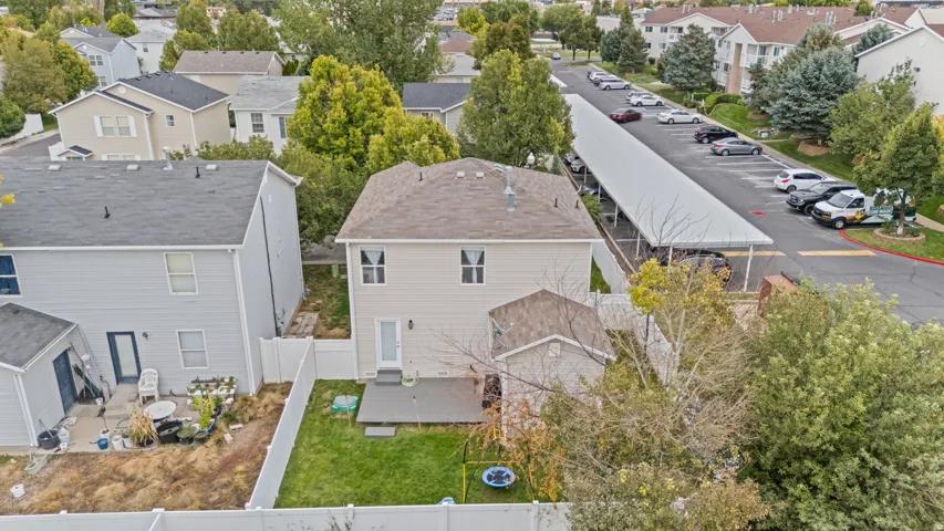 Two-story residential structure with a shingled roof, private fenced yard, and a ground-level patio