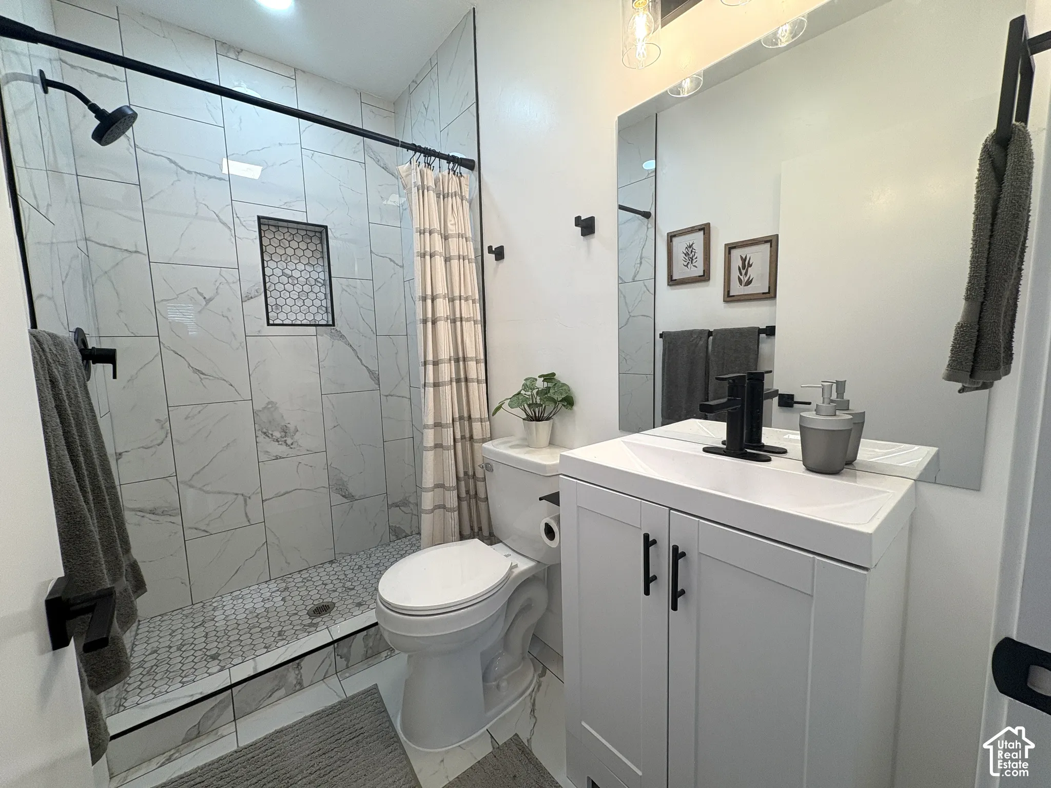 Tiled shower with a niche, white vanity, integrated sink, and black fixtures