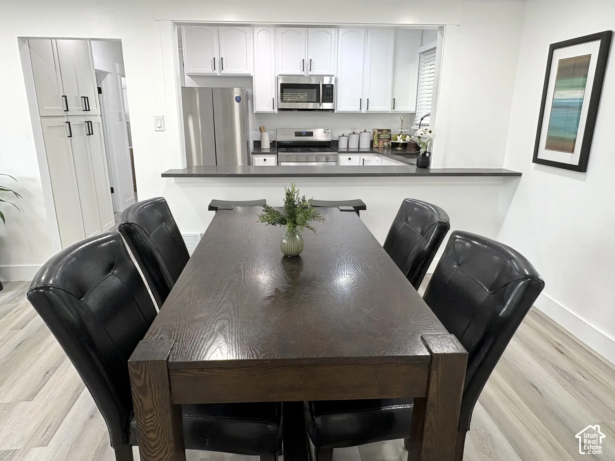 Kitchen featuring white cabinetry, stainless steel appliances, dark countertops, and a pass-through window
