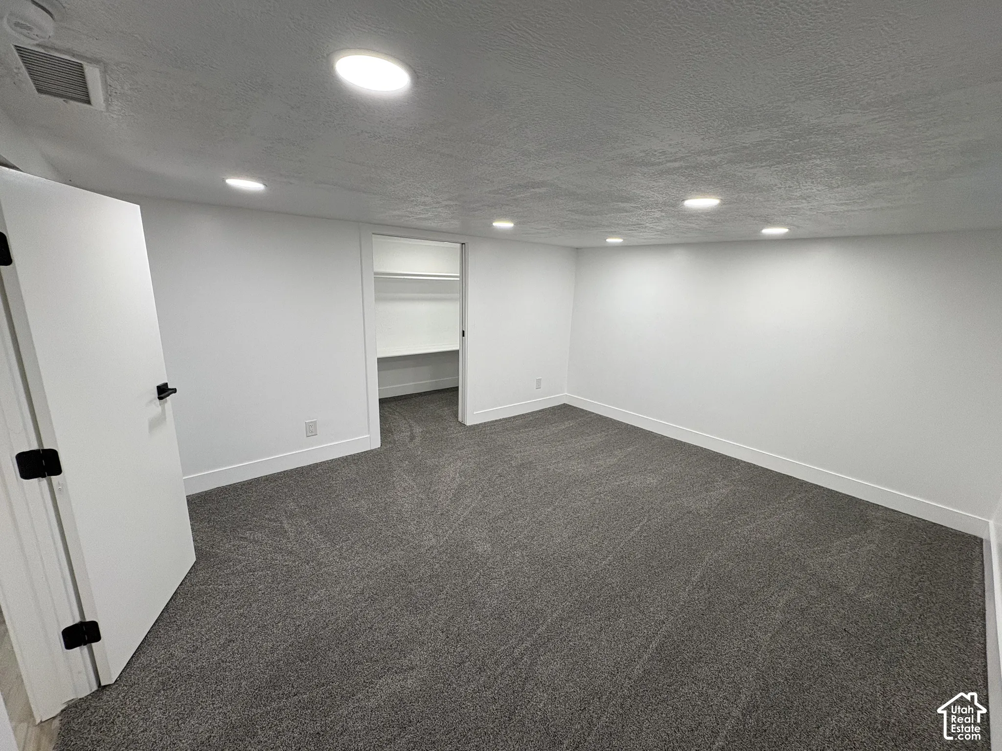 Recessed ceiling lighting, white walls, gray carpeting, white trim, and a built-in closet with shelving
