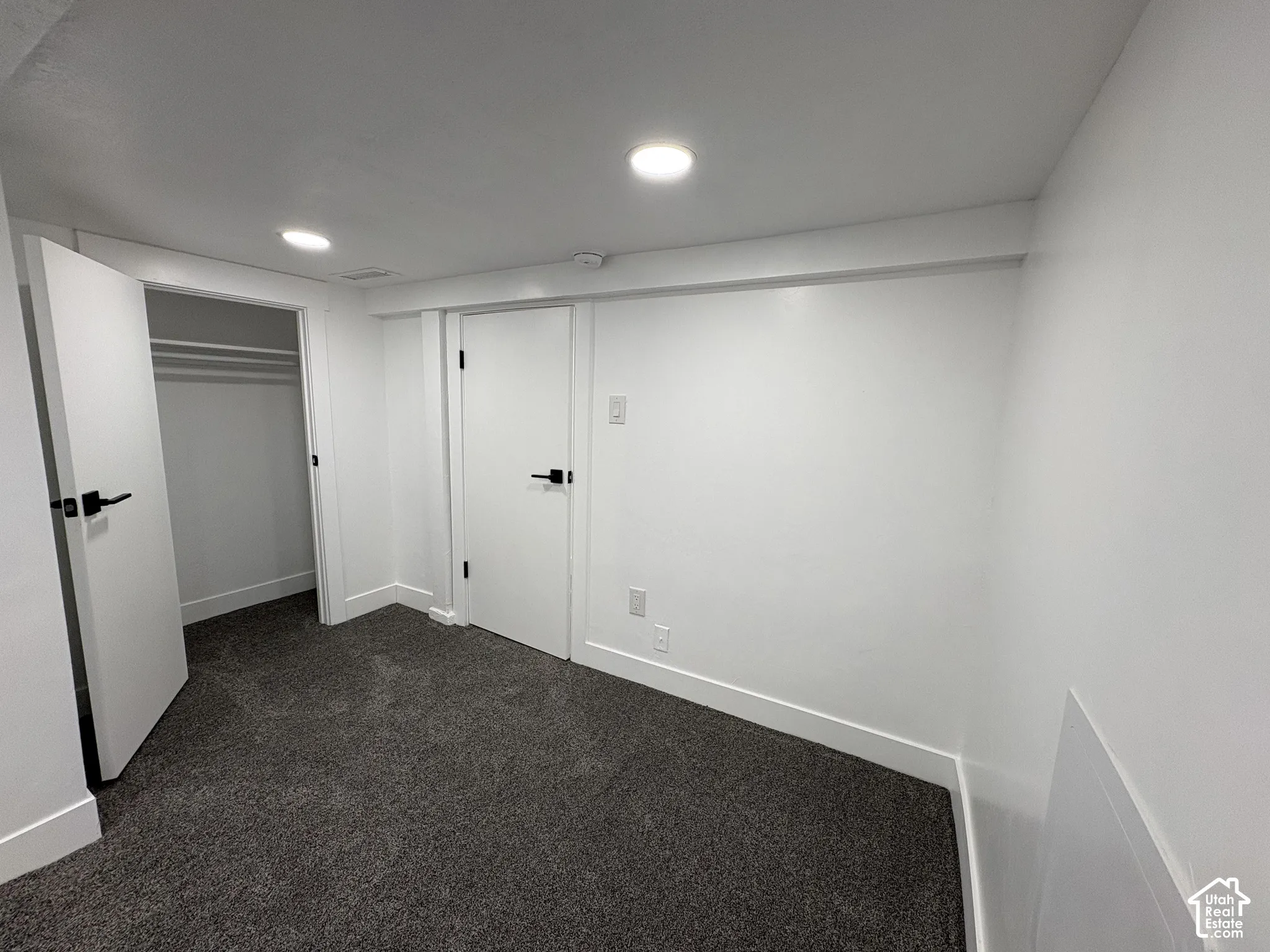 Recessed lighting, white walls, dark gray carpeting, white interior doors, and matte black hardware