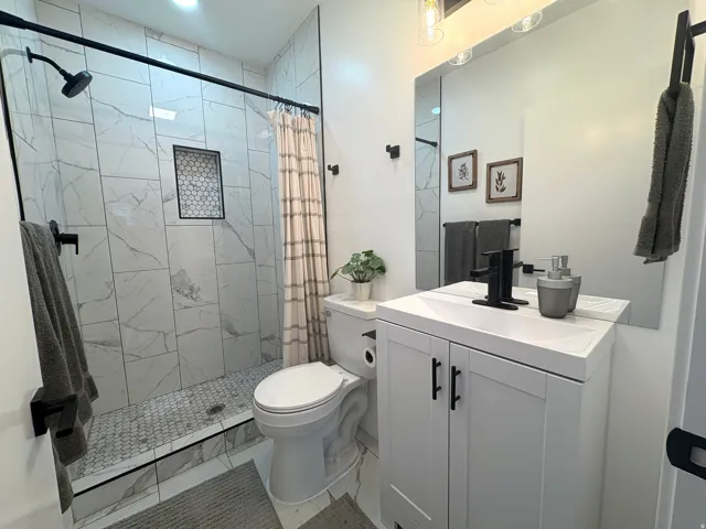Tiled shower with a niche, white vanity, integrated sink, and black fixtures