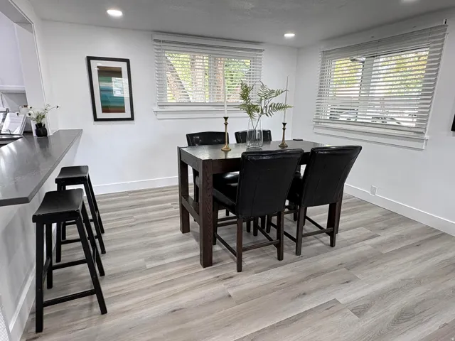 Open-concept dining area featuring wood-finish flooring, recessed lighting, and a breakfast bar with a solid surface countertop