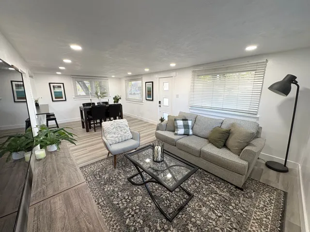 Recessed lighting, wood-finish flooring, white walls, multiple windows with blinds, and a white entry door with glass inserts