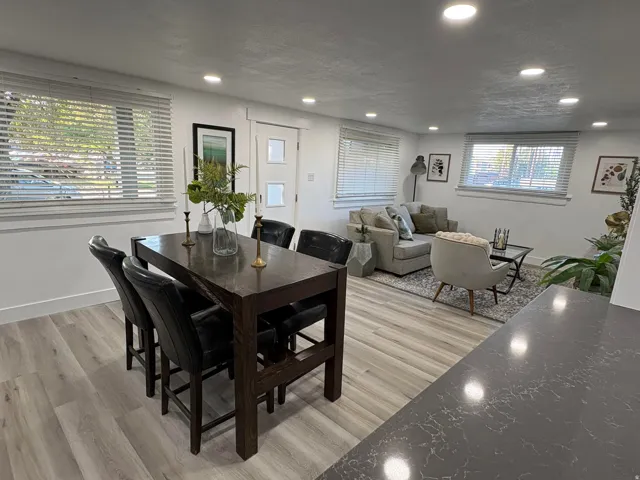 Recessed lighting, wood-finish flooring, white walls, multiple windows, and a dark stone-finish countertop