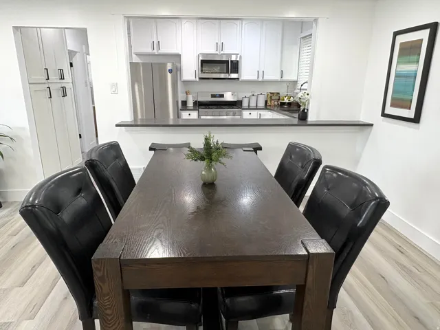Kitchen featuring white cabinetry, stainless steel appliances, dark countertops, and a pass-through window
