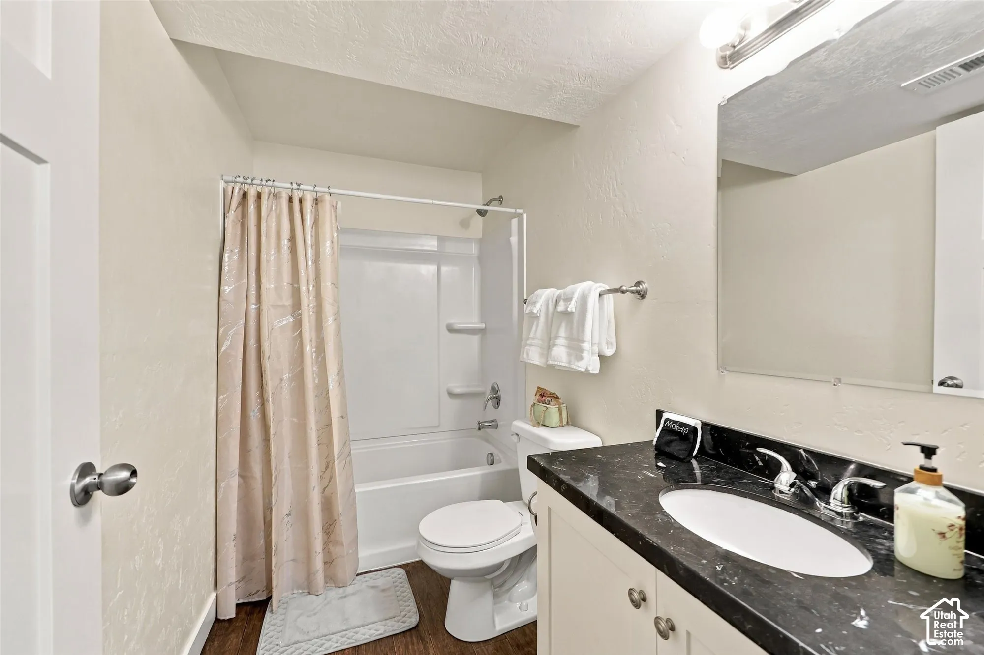 Bathroom featuring a single vanity with a dark countertop, an integrated sink, and white cabinetry