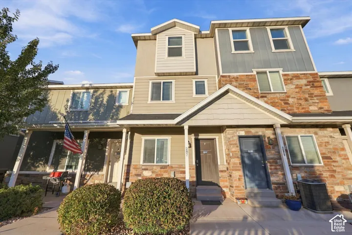 Multi-story townhome with mixed material facade, featuring stone veneer and horizontal siding