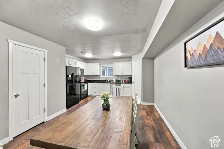 Open-concept living space featuring wood-finish flooring, white shaker cabinets, and a black appliance package