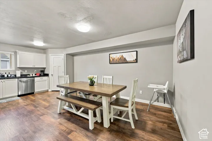 Wood-finish flooring throughout, white cabinetry with dark countertops, stainless steel dishwasher, and recessed lighting