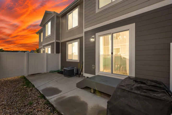 Concrete patio with white vinyl fencing and a sliding glass door