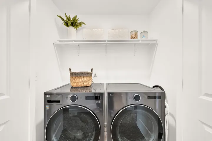 White laundry area featuring a shelf system and modern front-load appliances