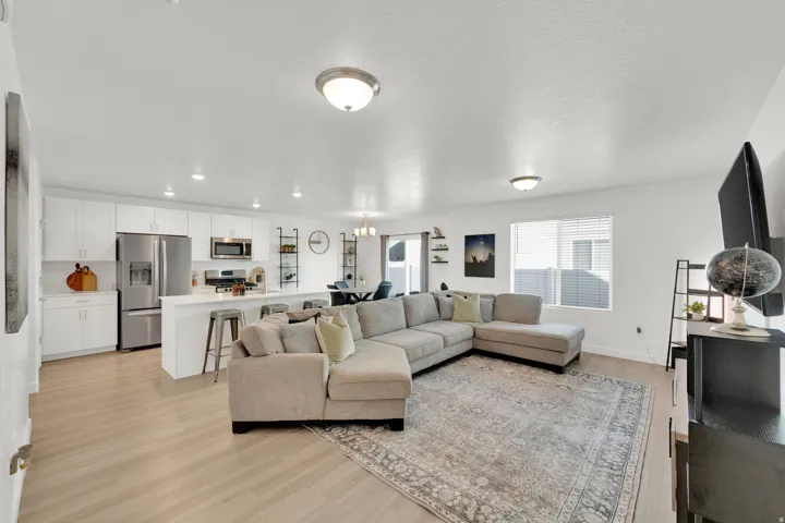 Open-concept living space featuring wood-finish flooring, recessed lighting, and a kitchen island with seating