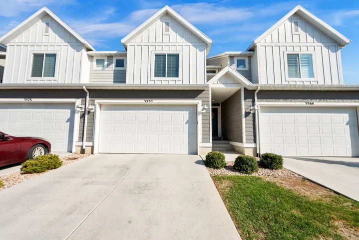 Modern townhome exterior featuring gray siding, white trim, gabled roofs, and an attached two-car garage