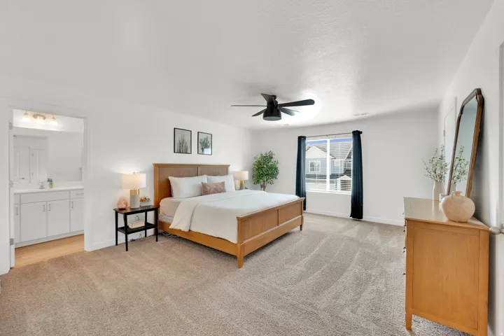 Spacious room with plush carpet flooring, a large window, and an attached bathroom featuring a vanity with white cabinetry