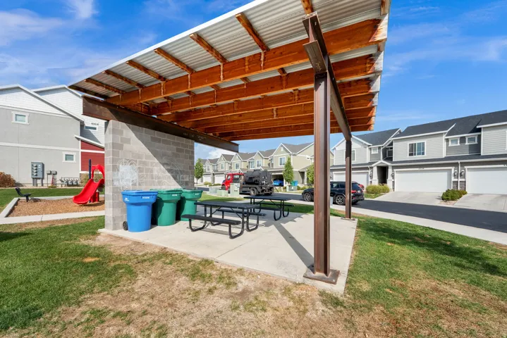 Covered outdoor gathering area featuring a corrugated metal roof supported by wood beams and metal posts