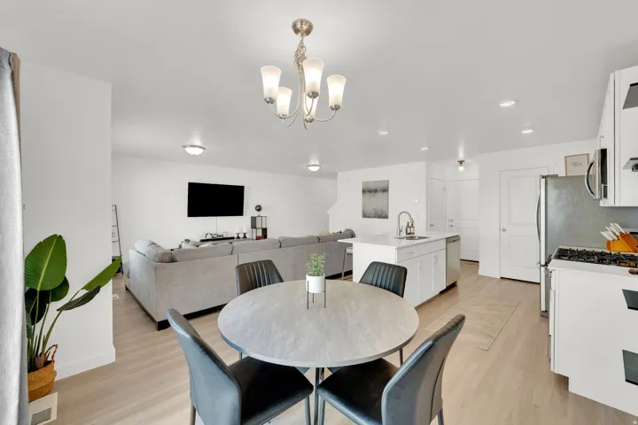 Open-concept living area with light wood-finish flooring, white cabinetry, a kitchen island, and stainless steel appliances