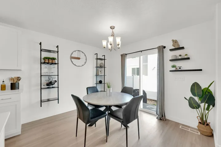 Sliding glass door, wood-finish flooring, white cabinetry, recessed lighting, and a multi-light chandelier