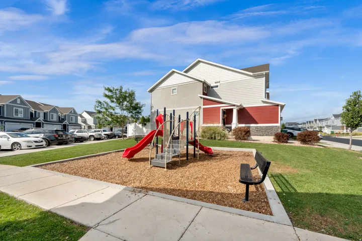 Community playground with a red slide, a bench, and wood chip ground cover