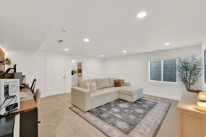 Recessed lighting, wood-finish desk, white painted walls, and a window with horizontal blinds