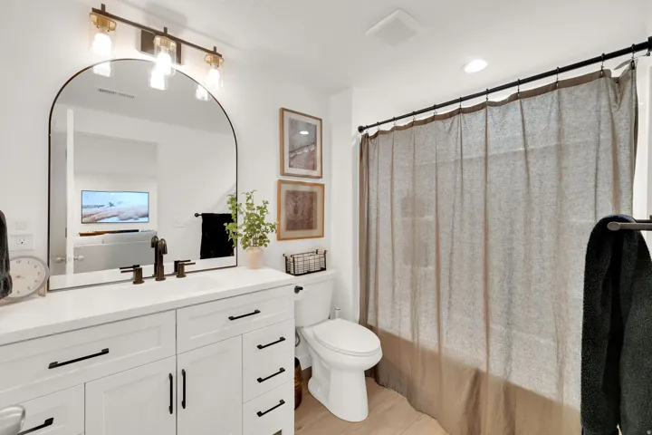 White vanity with dark hardware, a rectangular undermount sink, and a dark bronze faucet