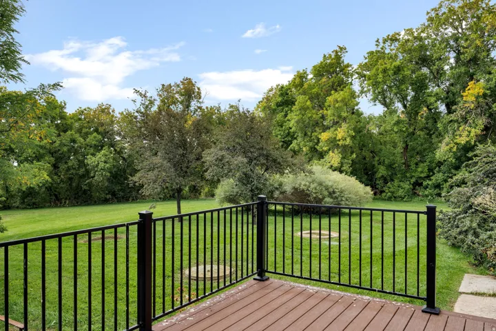 Composite decking with black metal railing, overlooking a large grass area with mature trees