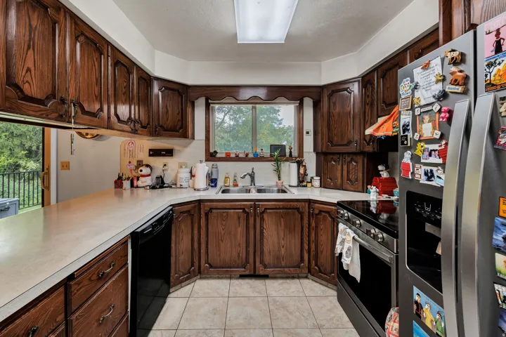U-shaped kitchen featuring wood cabinetry, light-toned countertops, and a double basin sink
