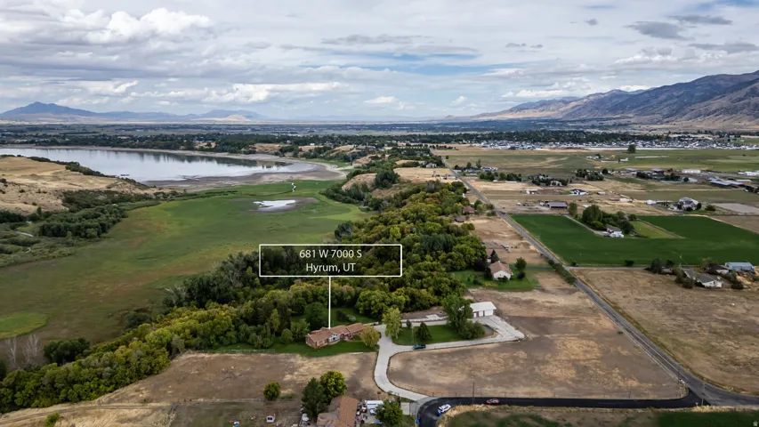 Expansive property featuring a single-story residence, mature trees, and proximity to a body of water