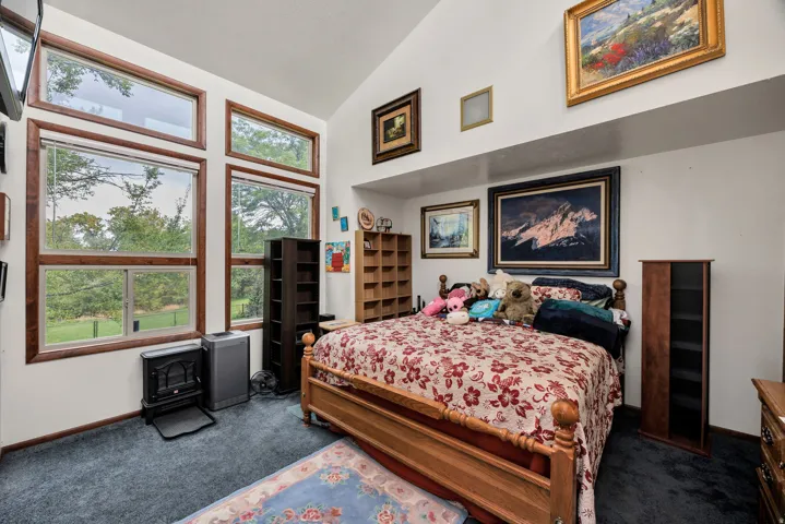 Vaulted ceiling with a recessed architectural ledge, featuring multiple transom windows and large picture windows with wood-finish framing