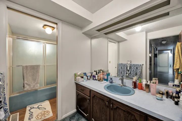 Bathroom vanity with a blue oval sink, a wall-mounted mirror, and wood-finish cabinetry