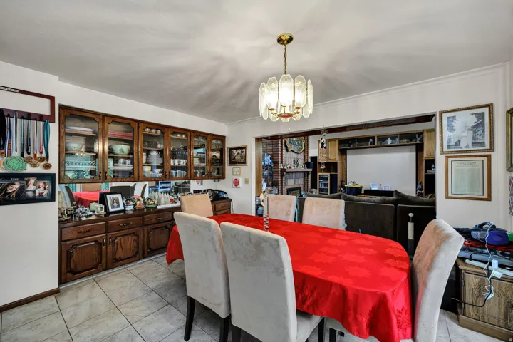 Recessed built-in cabinetry with glass-front uppers and wood-panel lower doors, tile flooring, and a decorative chandelier