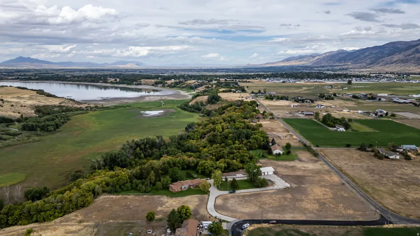Expansive landscape featuring a lake, mature trees, and distant mountains