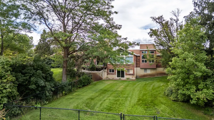 Expansive green lawn with mature trees and a chain-link fence