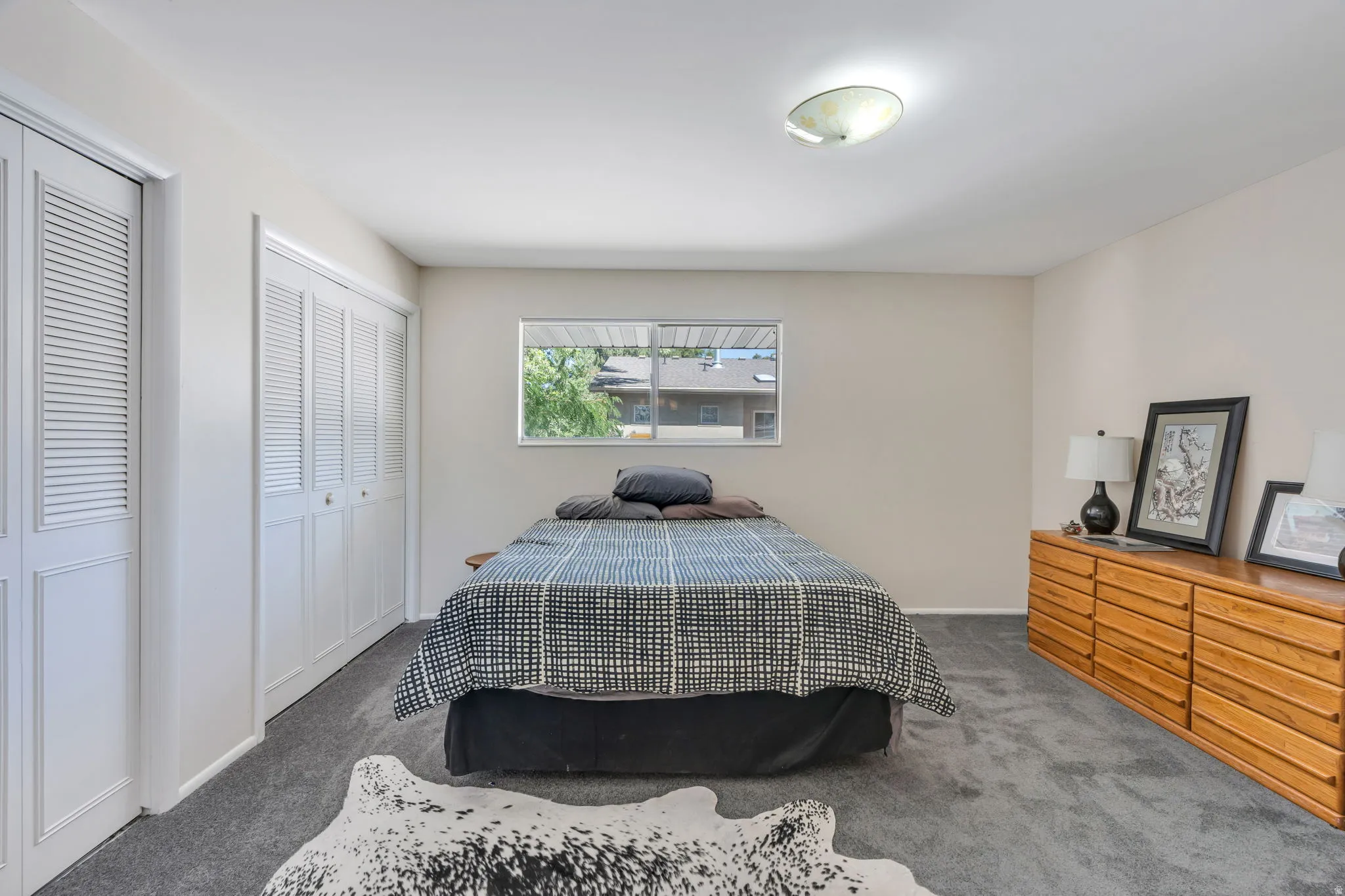 Dual bi-fold closet doors, wall-to-wall carpeting, recessed window, and flush mount lighting