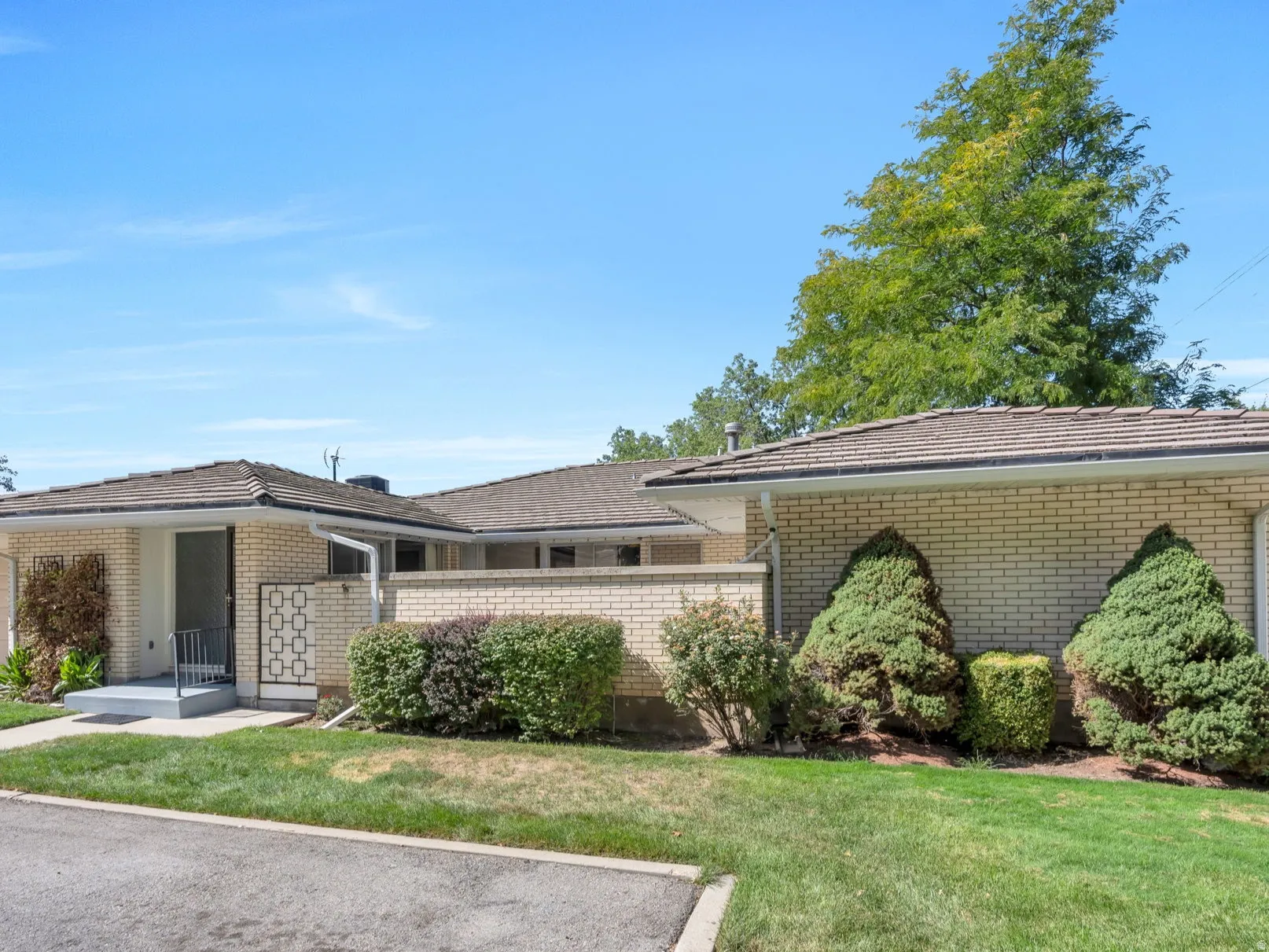 Brick exterior, dual garage doors, paved driveway, concrete entryway, and manicured landscaping