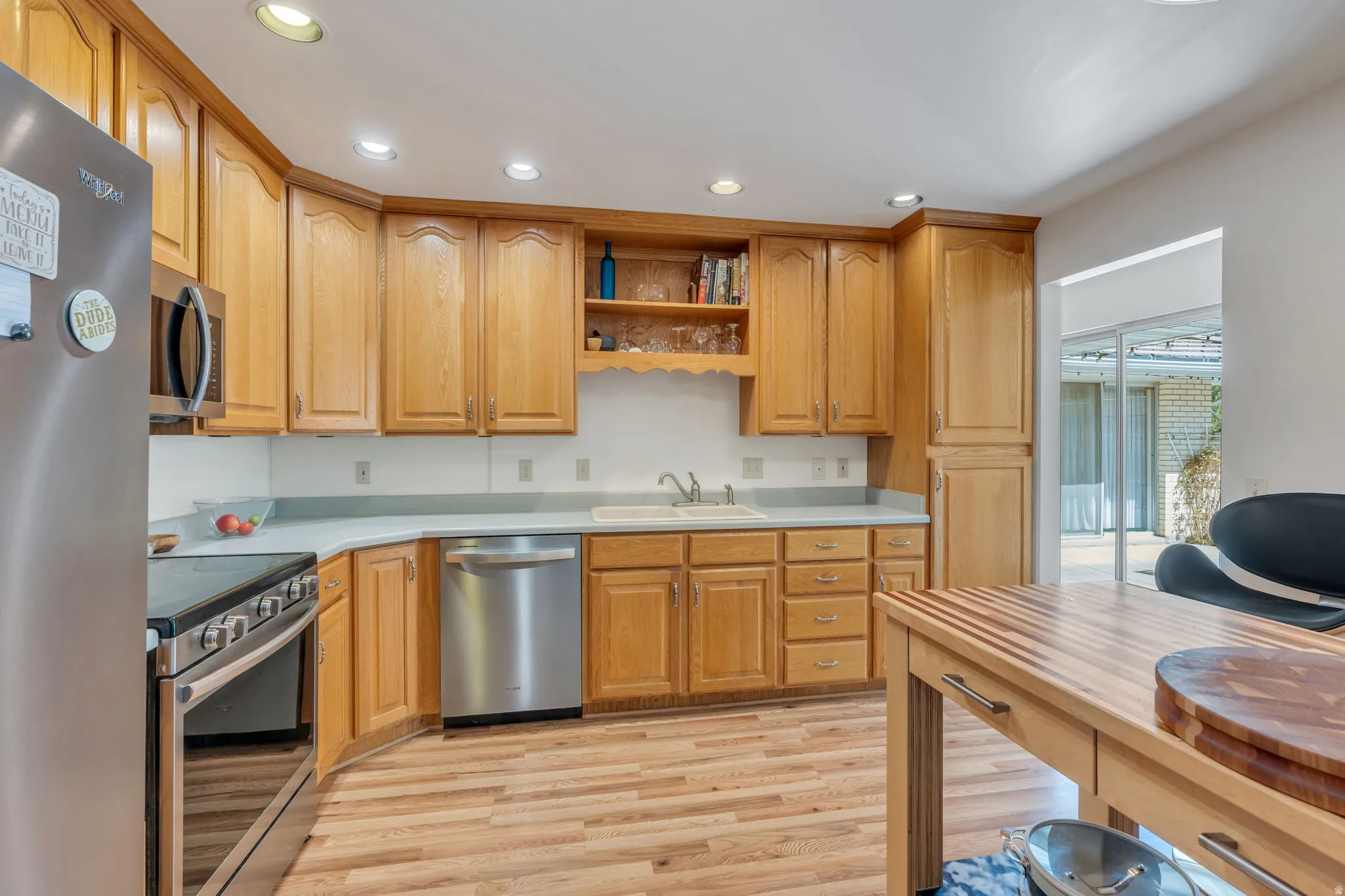 Kitchen featuring wood-finish flooring, recessed lighting, wood cabinetry, stainless steel appliances, and a built-in kitchen island