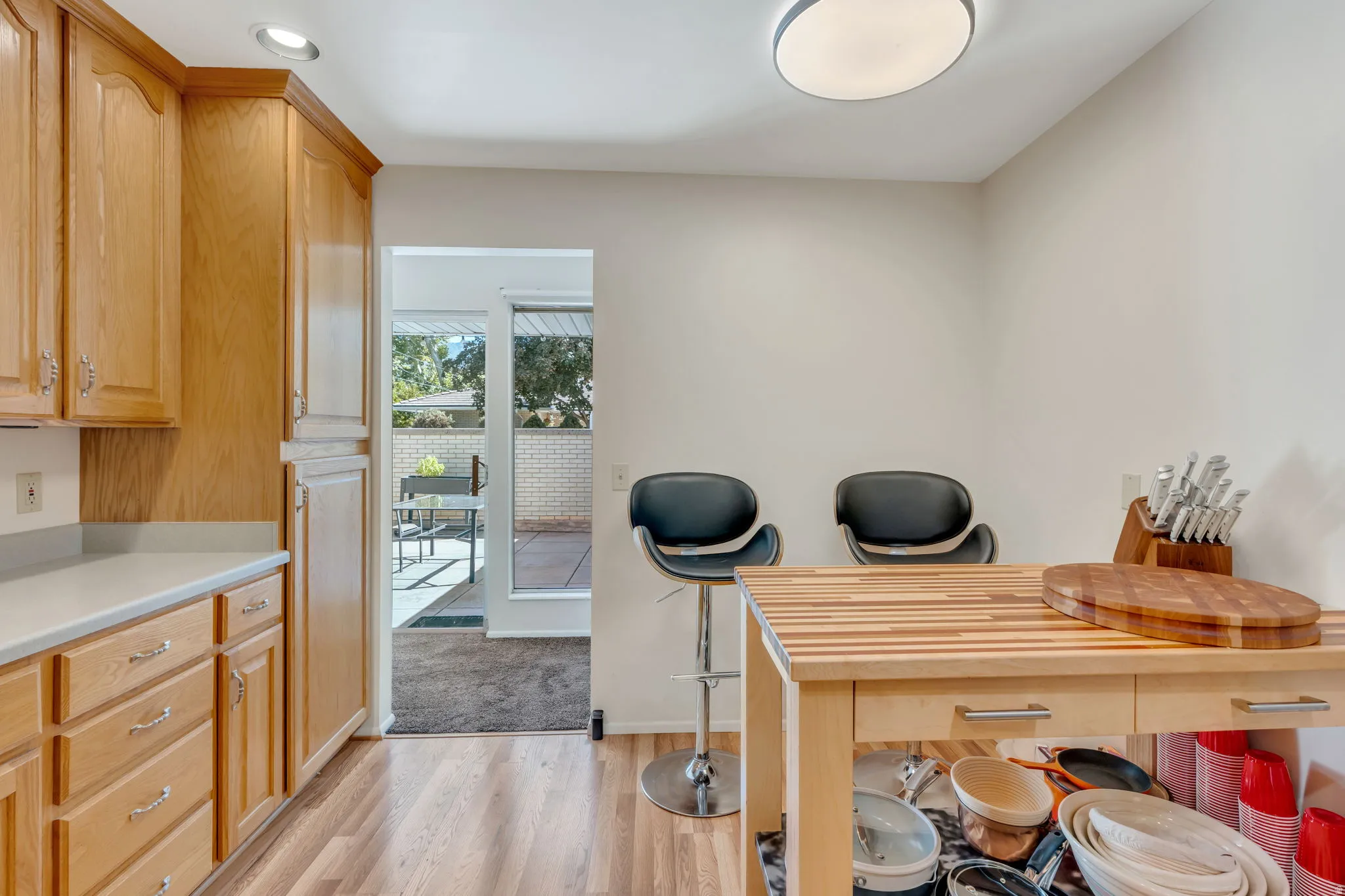 Wood-finish flooring, recessed ceiling lighting, light-toned cabinetry, light countertops, and glass patio doors