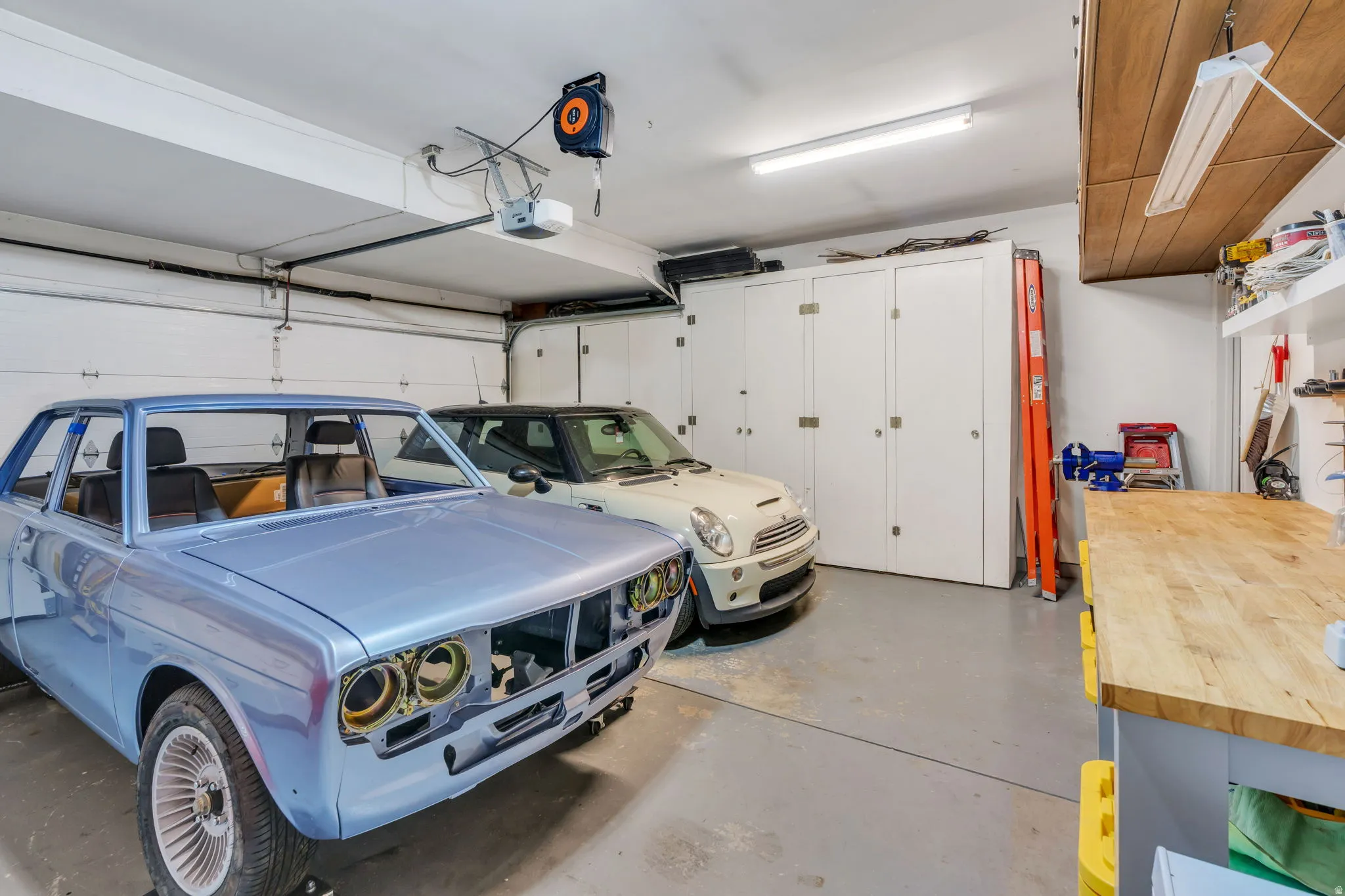 Garage with built-in storage cabinetry, a wood-finish workbench, and overhead lighting